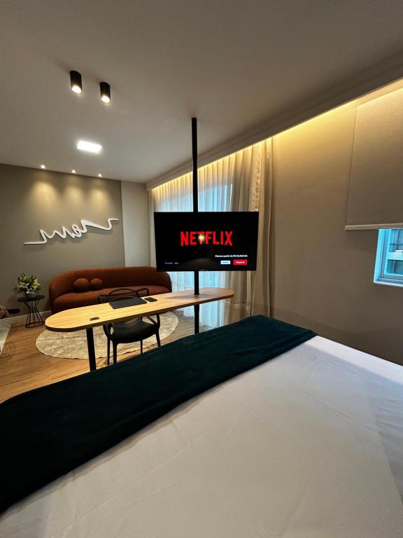 Habitación con cama y TV en la pared. en Flat Praia do Canto Iate Clube long Stay, en Vitória