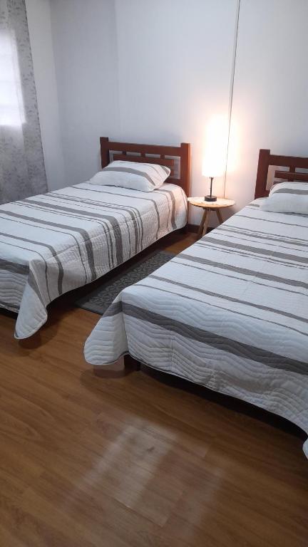 two beds in a bedroom with a lamp on a wooden floor at 2 beautiful Apartments in Downtown Risaralda Caldas 1 studio and 1 full apartment in Rizaralda