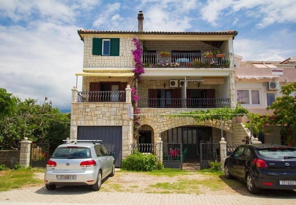a house with two cars parked in front of it at Apartments Juri in Sućuraj