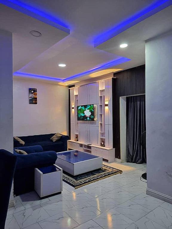 a living room with a couch and a tv at JKA 1-BEDROOM-Apart 24HRS POWER Unlimited WIFI , GARDEN PATIO AREA ,FREE DAILY HOUSEKEEPING in Lagos