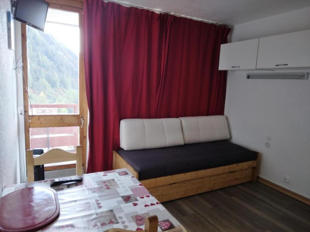 Cette petite chambre comprend un lit et un rideau rouge. dans l'établissement Résidence Saint Jacques A - Studio pour 2 Personnes 46, à Mâcot La Plagne