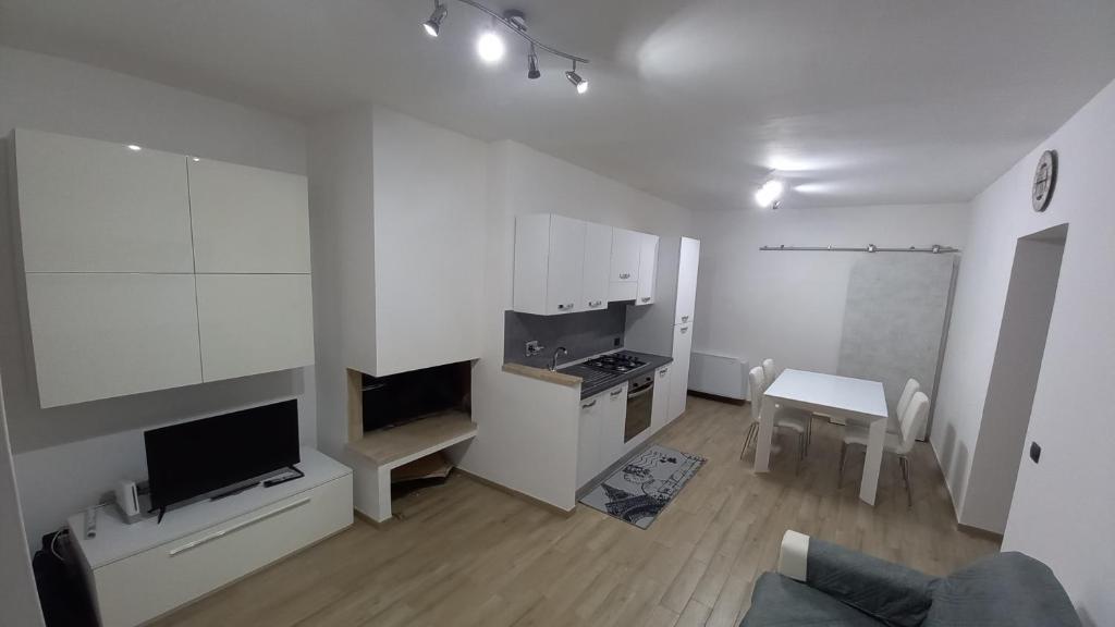 a kitchen with white cabinets and a living room at Casa di Sara in Pescasseroli