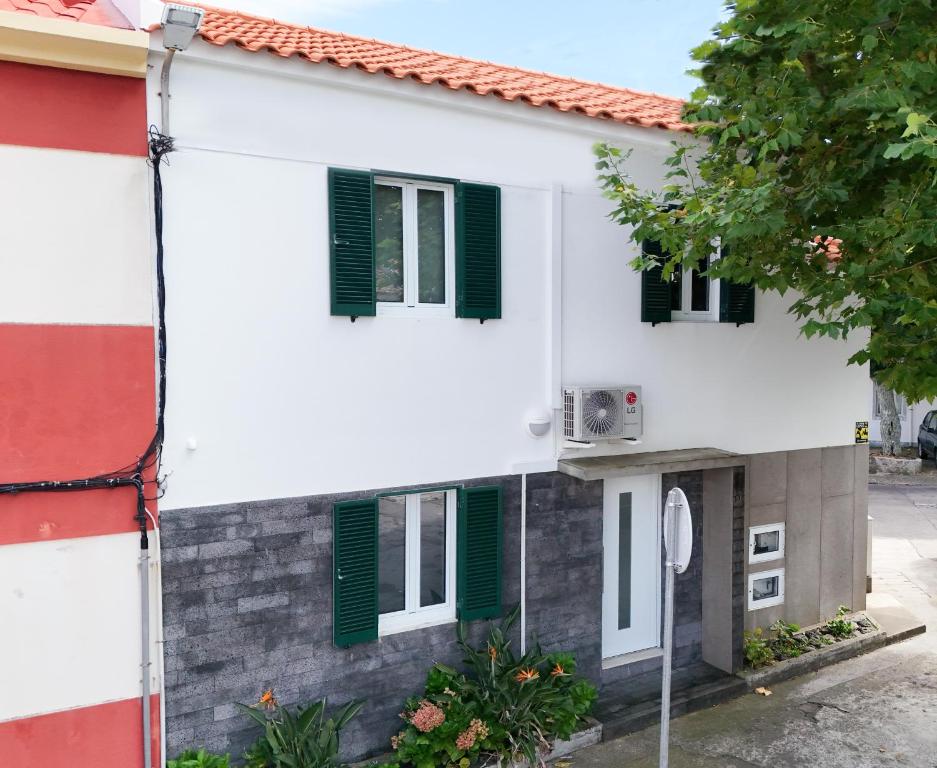 a white house with green shuttered windows at R&M Place in São Roque