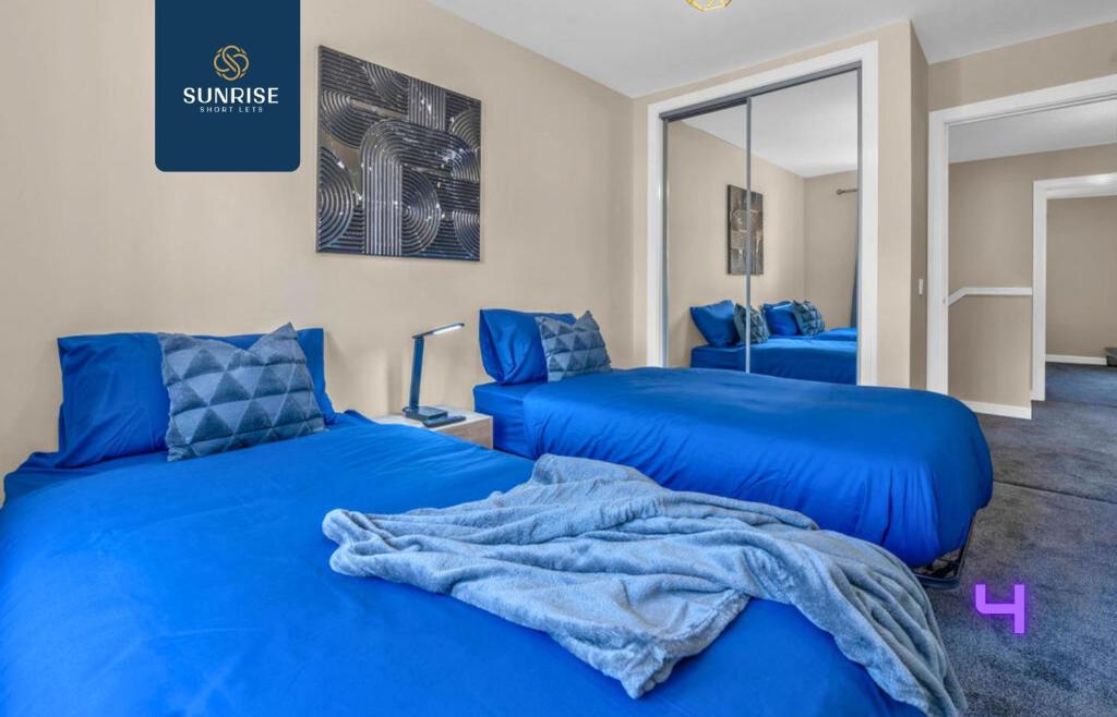 two blue beds in a room with a mirror at L1 - INVOICE and REDUCED PRICE only via SUNRISE SHORT LETS DUNDEE, Large 4 Bedroom House with 6 Beds and 3 bathrooms, TVs in each room, Free Parking, Fully Equipped, Local Amenities, Easy Ring Road Access, Special Rates in Dundee