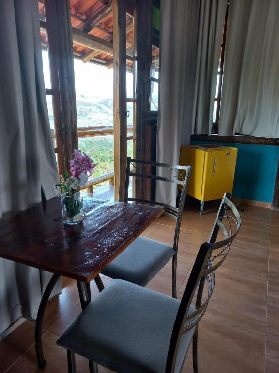 a wooden table with chairs and a vase of flowers on it at Pousada Cachoeiras do Cipó in Serra do Cipo
