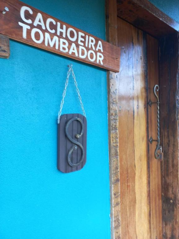 a sign hanging on a blue wall next to a door at Pousada Cachoeiras do Cipó in Serra do Cipo