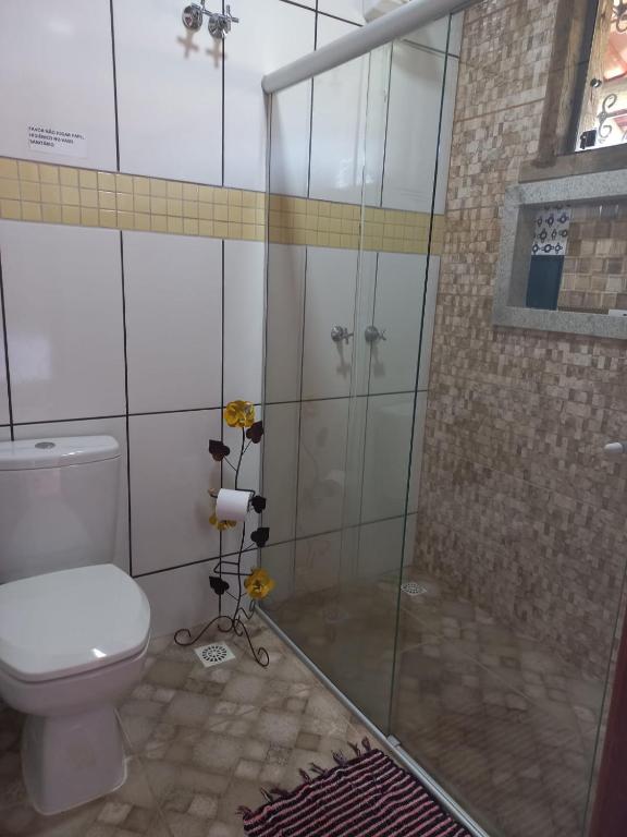 a bathroom with a toilet and a glass shower at Pousada Cachoeiras do Cipó in Serra do Cipo
