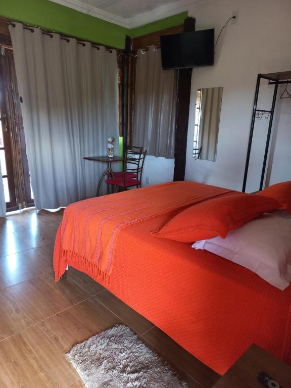 a bedroom with a red bed and a table at Pousada Cachoeiras do Cipó in Serra do Cipo