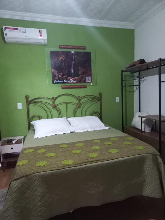 a bedroom with a green wall with a bed at Pousada Cachoeiras do Cipó in Serra do Cipo