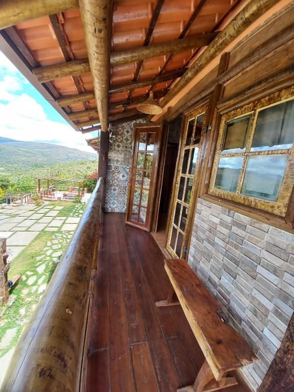 a porch of a wooden house with a bench on it at Pousada Cachoeiras do Cipó in Serra do Cipo