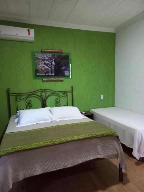 a bedroom with two beds and a green wall at Pousada Cachoeiras do Cipó in Serra do Cipo
