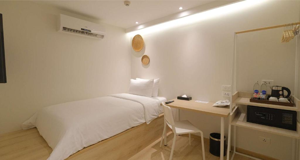 A compact white bedroom with a double bed, desk and in-room refreshments.