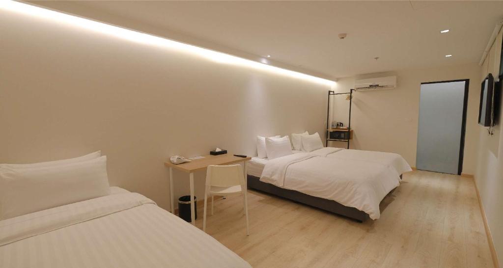 A long multi-bed room with a small desk, chair and bathroom entrance.