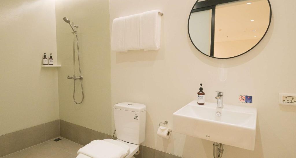 A compact bathroom combines an open shower area, toilet, and wall-mounted sink.