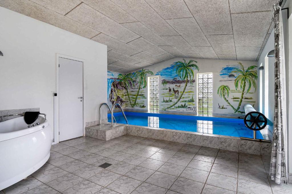 ein Badezimmer mit Badewanne und Palmen an der Wand in der Unterkunft Nice Pool House On Scenic Møn in Stege