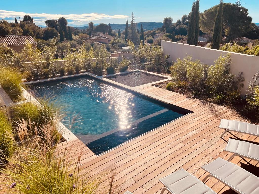 - une piscine sur une terrasse en bois avec des chaises dans l'établissement Villa paisible entre Avignon et Nimes avec piscine chauffée sur demande, à Rochefort-du-Gard