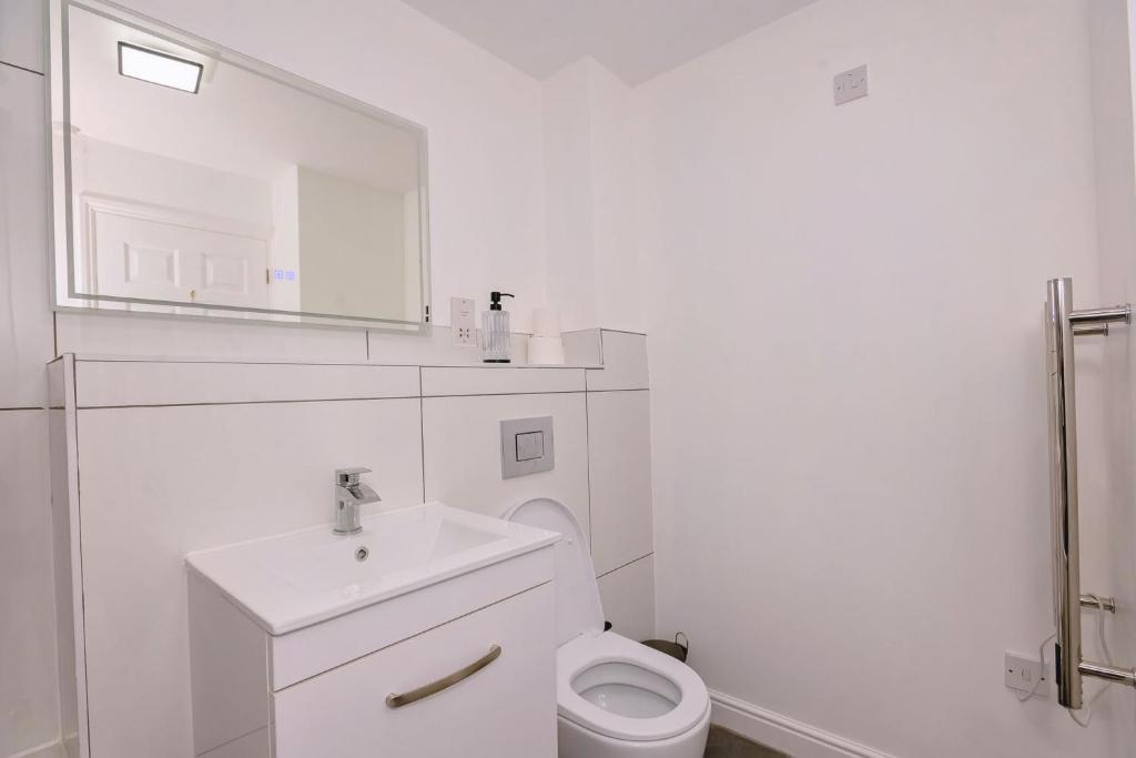 a white bathroom with a sink and a toilet at Bright apartment in London
