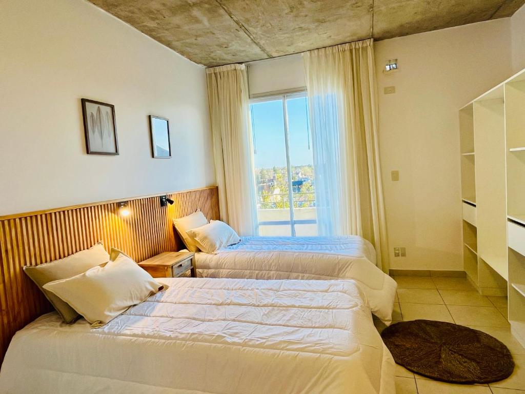 Dos camas en una habitación de hotel con ventana. en Departamento monoambiente, en Luján