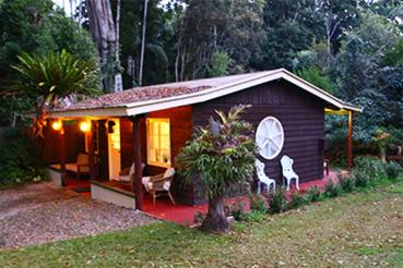 a small house with two chairs and a porch at Curtis Cottage in Mount Tamborine
