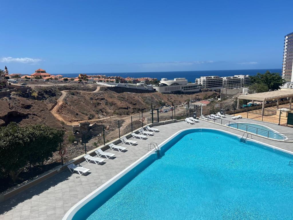 Una piscina con sillas y el océano al fondo. en Playa Paraiso vue océan, en Playa Paraiso