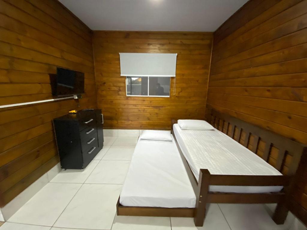 a room with two beds in a room with wooden walls at Residencial Tamagi in Florianópolis