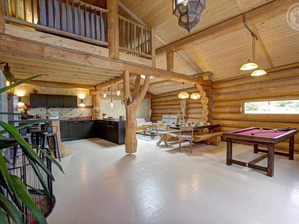 una grande stanza con tavolo da ping pong in una baita di tronchi di Gîte de charme avec poêle à bois, billard et terrasse dans les Monts du Forez - FR-1-496-313 a Saint-Jean-Soleymieux