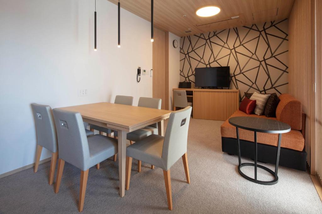 a dining room with a table and chairs and a couch at Tokyu Vacations Osaka Midosuji in Osaka