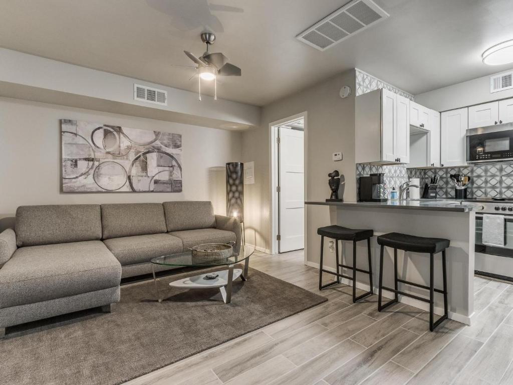 a living room with a couch and a table and a kitchen at Quiet Modern Heavenly Paradise Love and Balcony Near Lake, Mall, Food, Entertainment! in Oklahoma City
