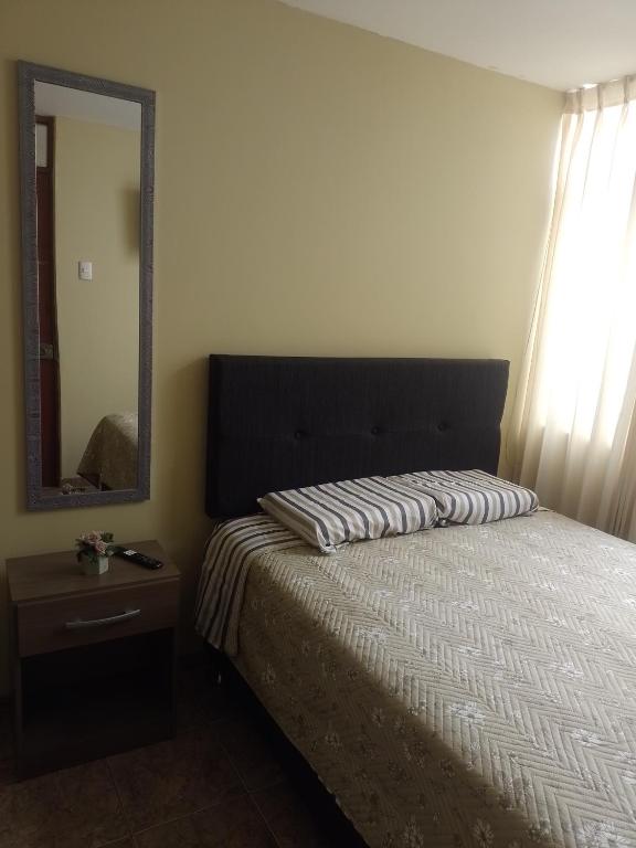 a bedroom with a bed with a mirror and a dresser at Acogedora habitación in Trujillo