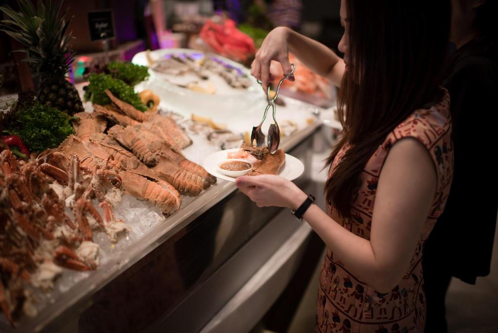 a woman is eating food at a buffet at The Berkeley Hotel Pratunam in Bangkok