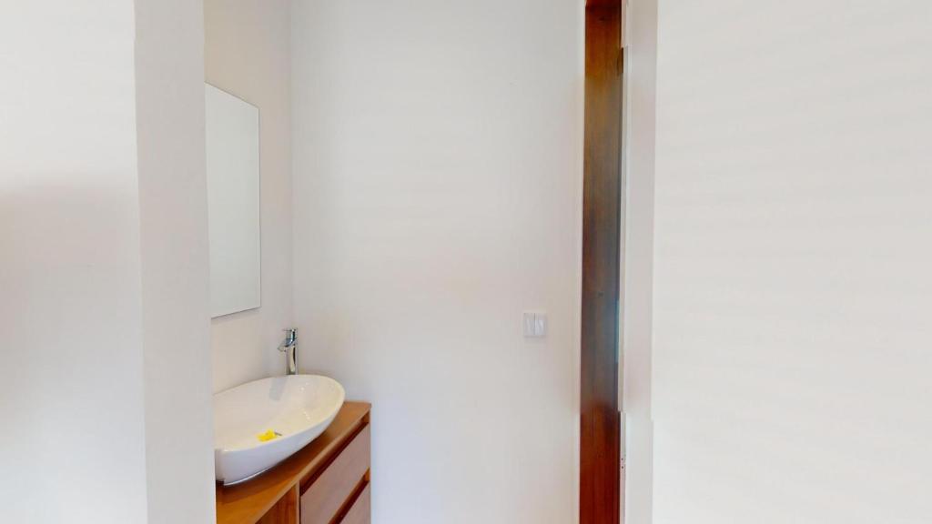 a white bathroom with a sink and a mirror at Segara Seaside Resort in Nusa Lembongan