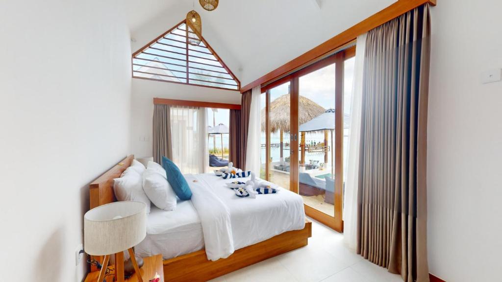 a bedroom with a bed and a large window at Segara Seaside Resort in Nusa Lembongan