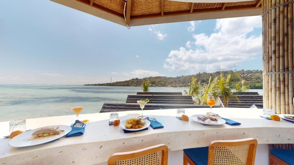 a table with food and the ocean in the background at Segara Seaside Resort in Nusa Lembongan