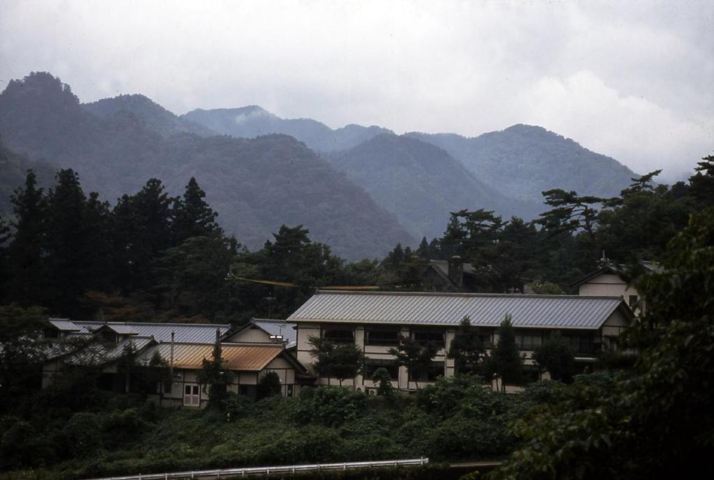 a building with mountains in the background at Nikko Tokanso in Nikko