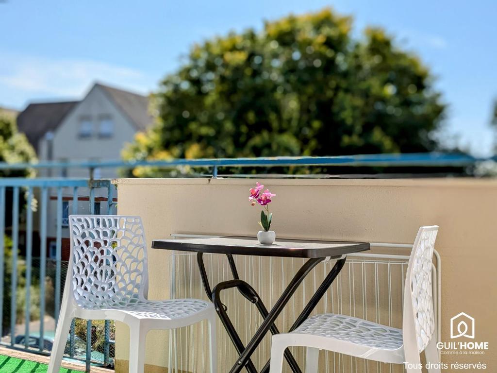une table avec deux chaises et un vase de fleurs sur le balcon dans l'établissement La Levée - Balcon ensoleillé - Parking gratuit rue, à Orléans