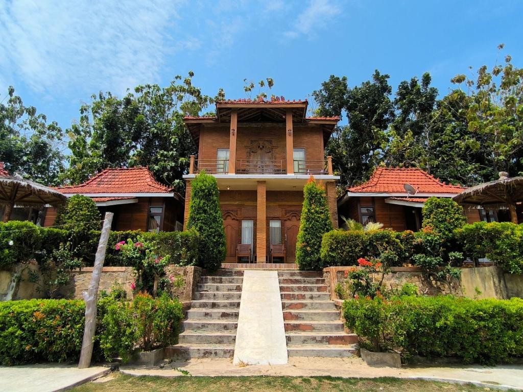 a large house with stairs in front of it at Sunrise Sea Hill Cottages in Karimunjawa