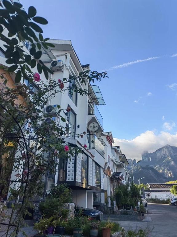 a white building with a clock on it at Flower Whisperer Homestay Tianmenshan Store free airport and station pick-up in Zhangjiajie