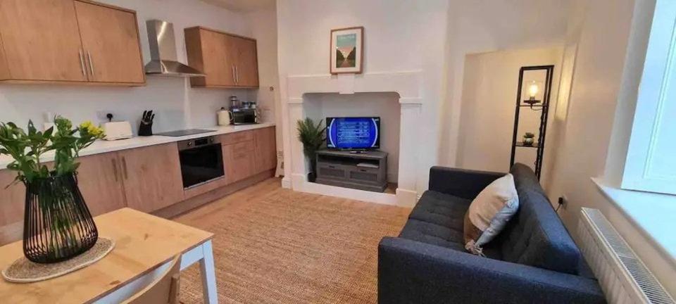 Peaceful apartment with courtyard in town centre في تيتبري: غرفة معيشة مع أريكة زرقاء وتلفزيون