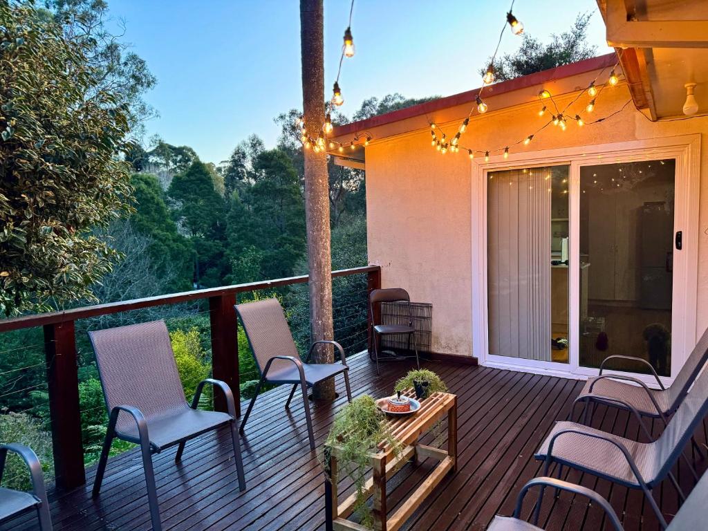 a deck with chairs and a table and lights at Belgrave Hillside Zen Retreat in Belgrave
