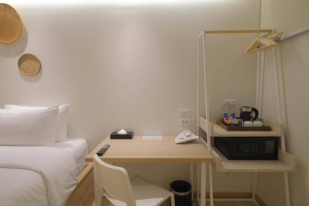 A compact guest-room desk sits beside the bed with a kettle station and open clothes rail.