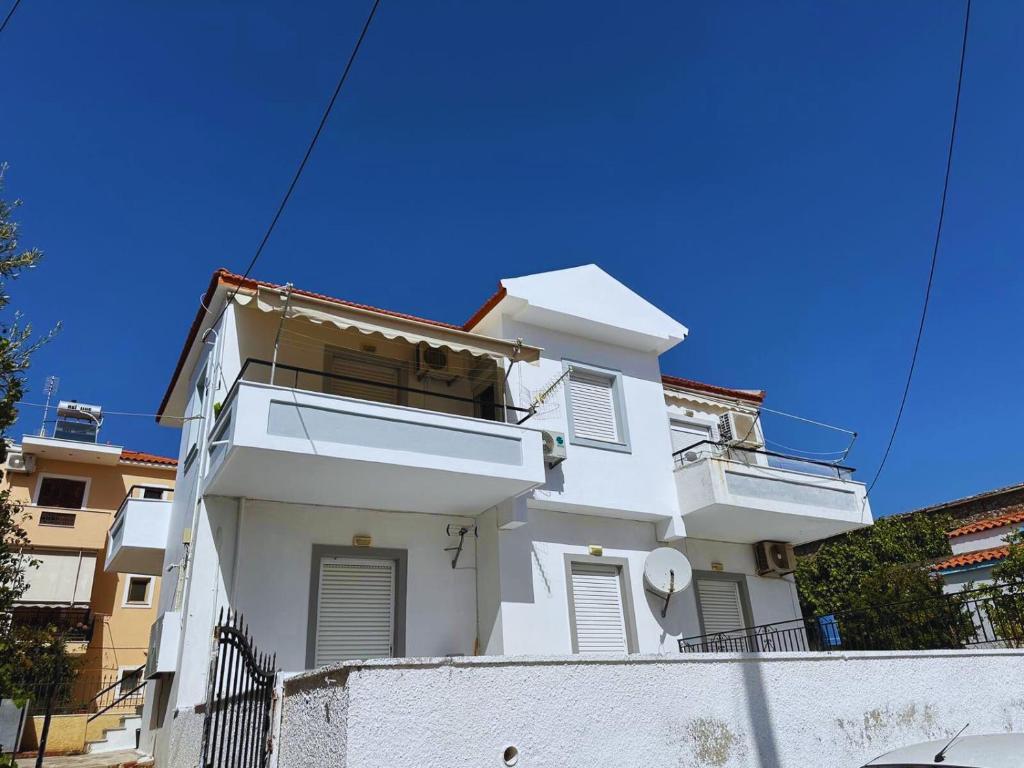 a white building with a blue sky in the background at Lydias apartment in Panagioúda