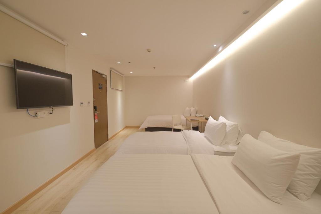 A bright twin room contains two neatly made beds and a wall-mounted television.
