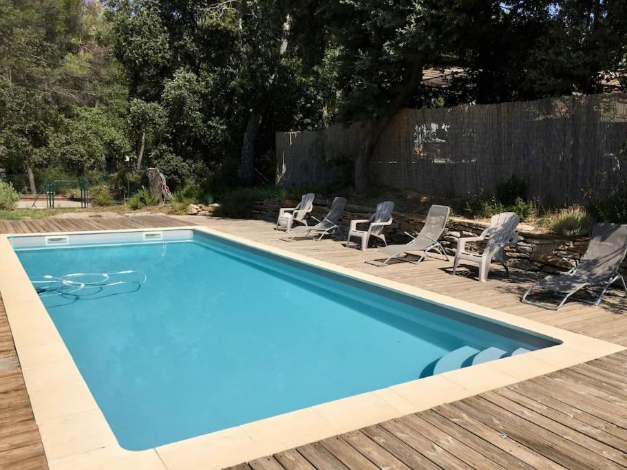 une piscine bleue avec des chaises et une clôture dans l'établissement Villa Family - Clim, Piscine & Pétanque, à Pourrières