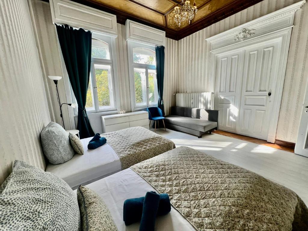 a bedroom with two beds and a couch and windows at Villa Sartorius - luxuriös und geräumig wohnen nahe Göttingen in Bovenden