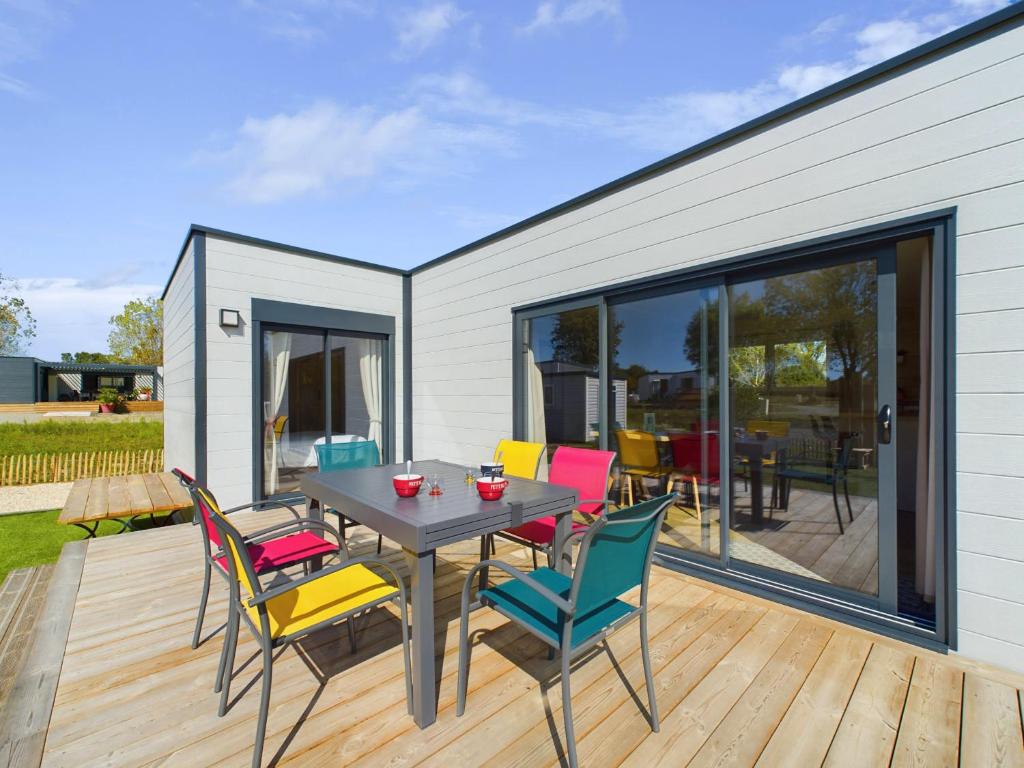 a patio with a table and chairs on a deck at Chalet pour 4 - Domaine avec piscine in Saint-Gilles-Croix-de-Vie