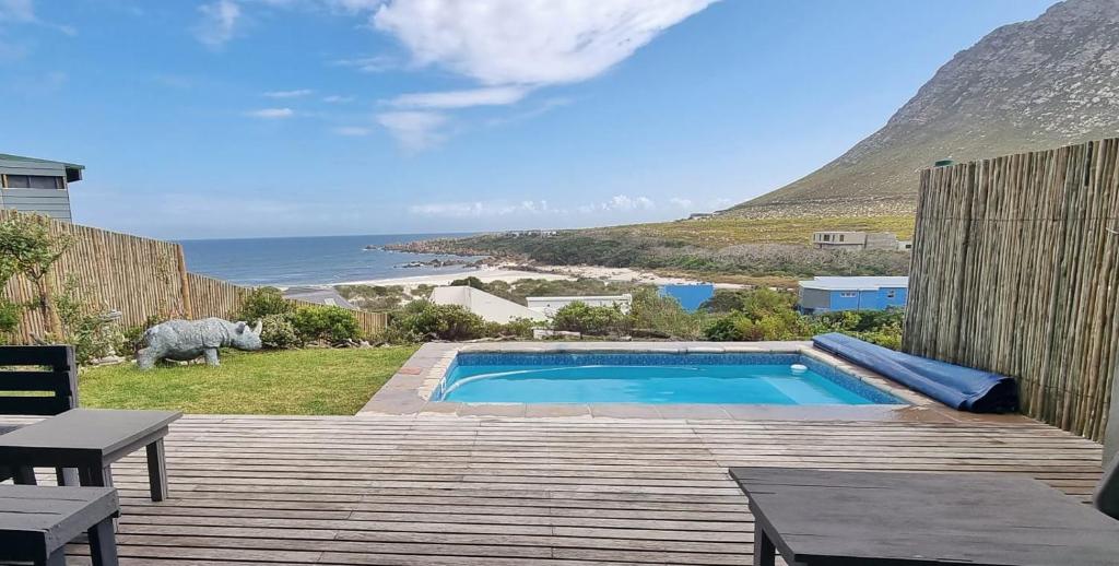 a swimming pool on a deck with a view of the ocean at Hilltop Heaven, Walk to beach, Pool, Ocean & River views in Pringle Bay
