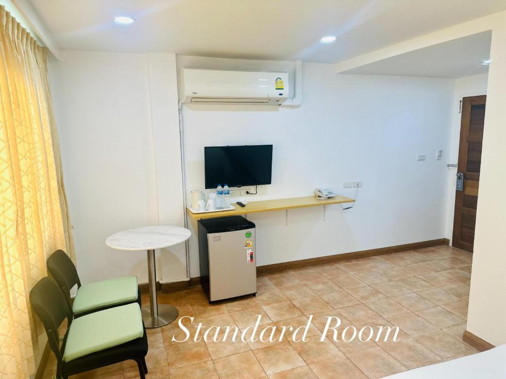 a room with a desk and a tv and a chair at Surin Bay Inn in Surin Beach