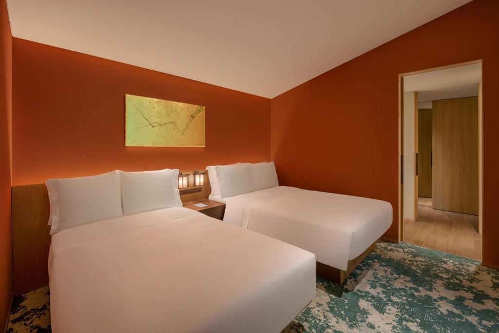 two beds in a hotel room with orange walls at Shisui, a Luxury Collection Hotel, Nara in Nara