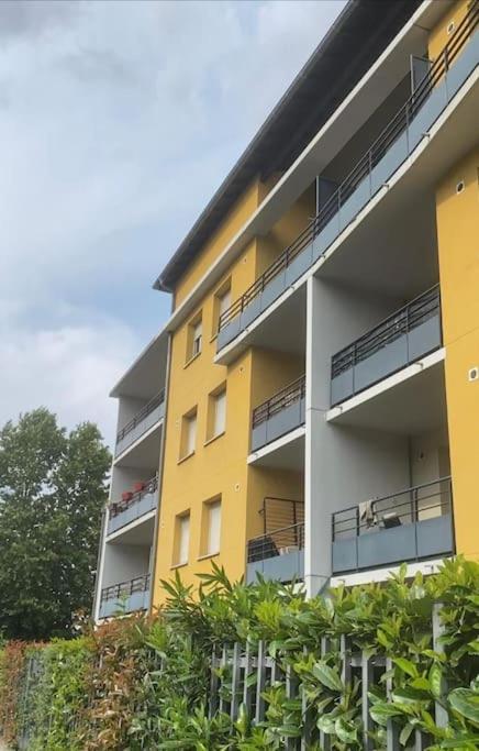 un immeuble d'appartements jaune avec balcon et plantes dans l'établissement Le Fronton - Confortable T2 - Piscine, à Toulouse