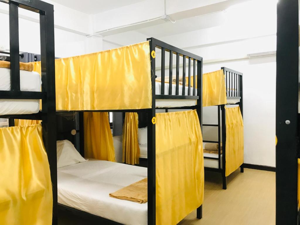 een groep stapelbedden in een kamer met gele gordijnen bij Silom Guesthouse in Bangkok